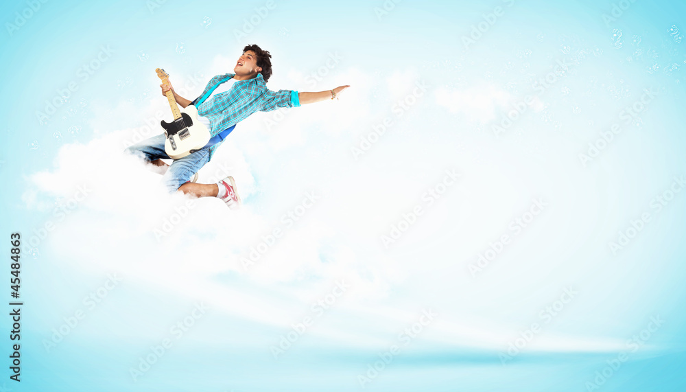 young man playing on electro guitar and jumping