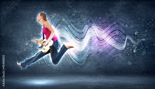 young woman playing on electro guitar and jumping photo