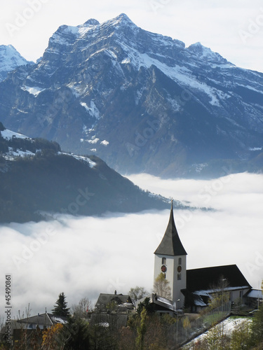 Rural church in Amden against snowy Alps, Switzerland