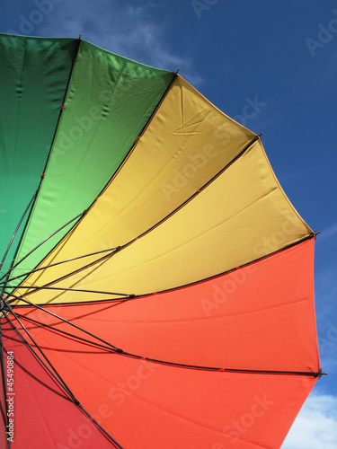 Spectrum colored umbrella against blue sky