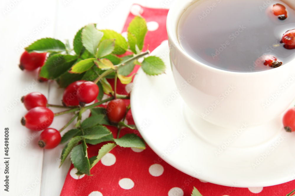 cup of tea with hip roses, on wooden table cup of tea with hip roses, on wooden table