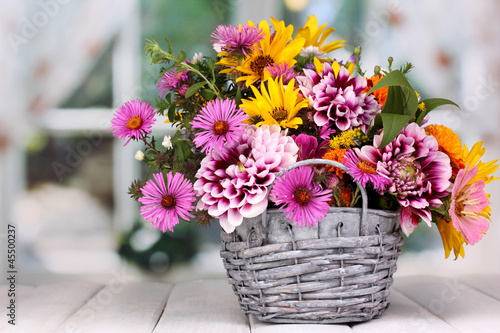 Fototapeta Naklejka Na Ścianę i Meble -  beautiful bouquet of bright flowers in basket on wooden table