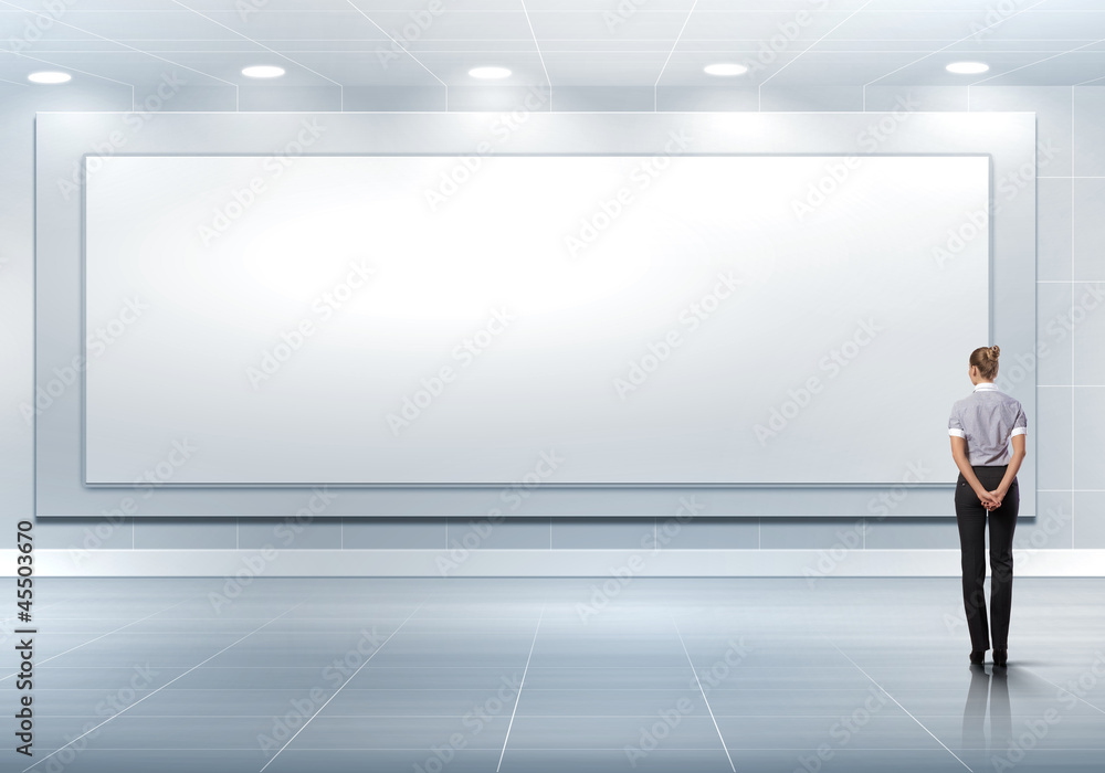 Business person standing near a blank billboard Business person standing near a blank billboard