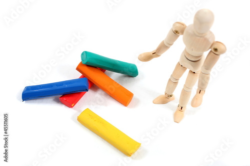 Manikin man standing at colourfull clay bars