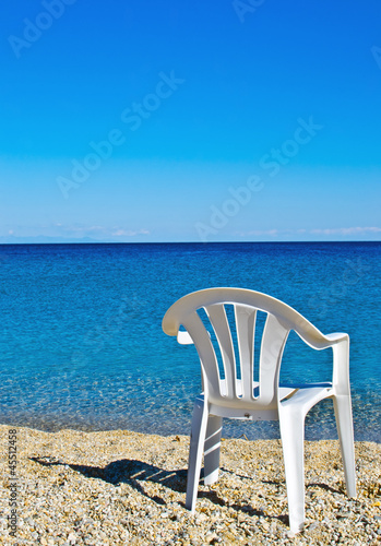 plastic beach chair on shore near sea