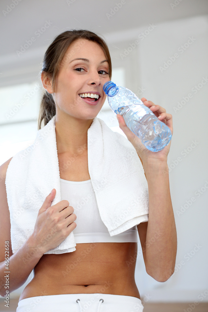 Cheerful fitness girl drinking water after exercising Cheerful fitness girl drinking water after exercising