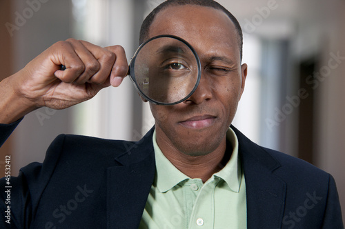 Black Man Looking through a magnifying glass