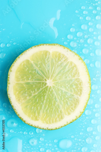 Slice of lime with drop on blue background