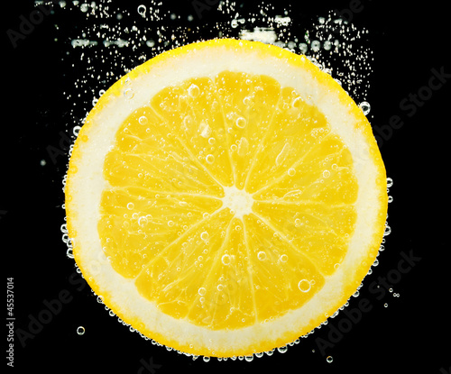 slice of orange in the water with bubbles, on black background