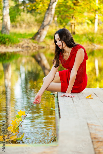 beautiful girl in the water leads autumn bush