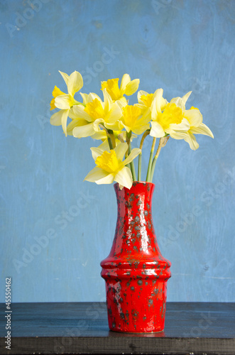 red vase on table with spring narcissus