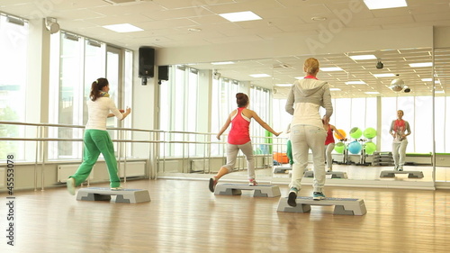 Group doing exercise on step boards in gym