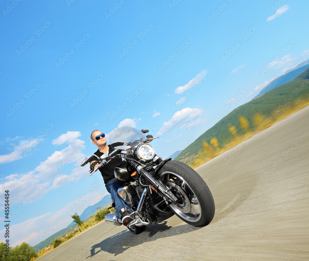 Biker riding a customized motorcycle on a road Biker riding a customized motorcycle on a road