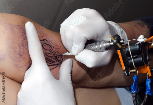 Tattoo artist makes the tattoo on arm