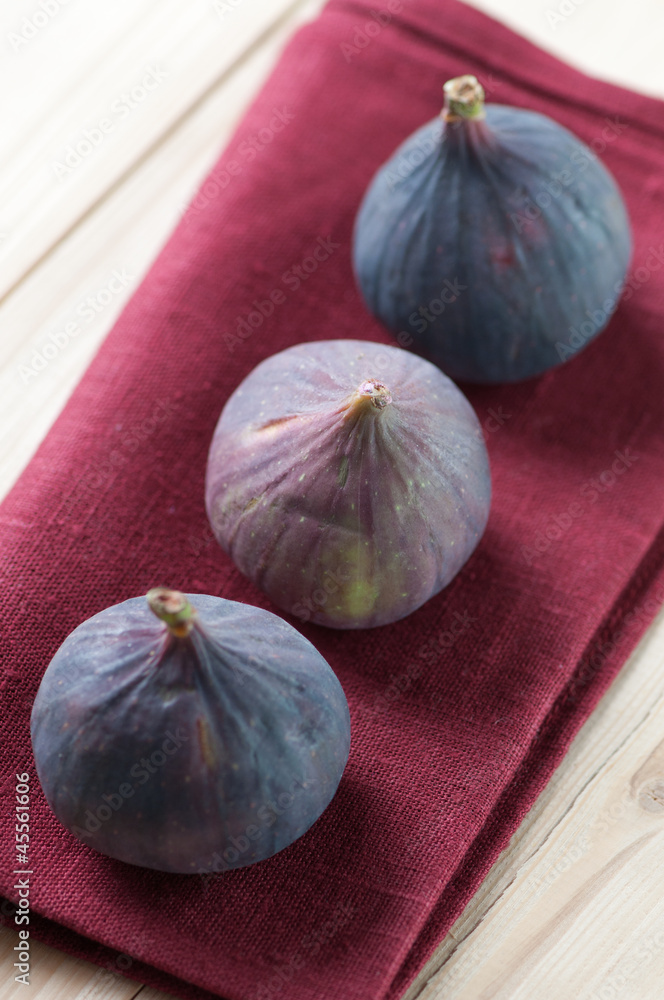 Fototapeta premium Ripe figs on a lilac serviette, vertical shot