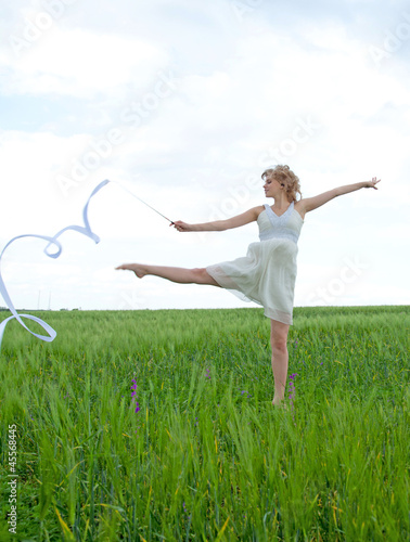 Beautiful young woman on a green meadow with a gymnastic ribbon