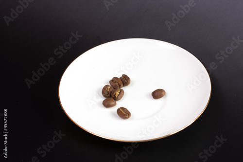 coffee grain on a round white plate on a black background