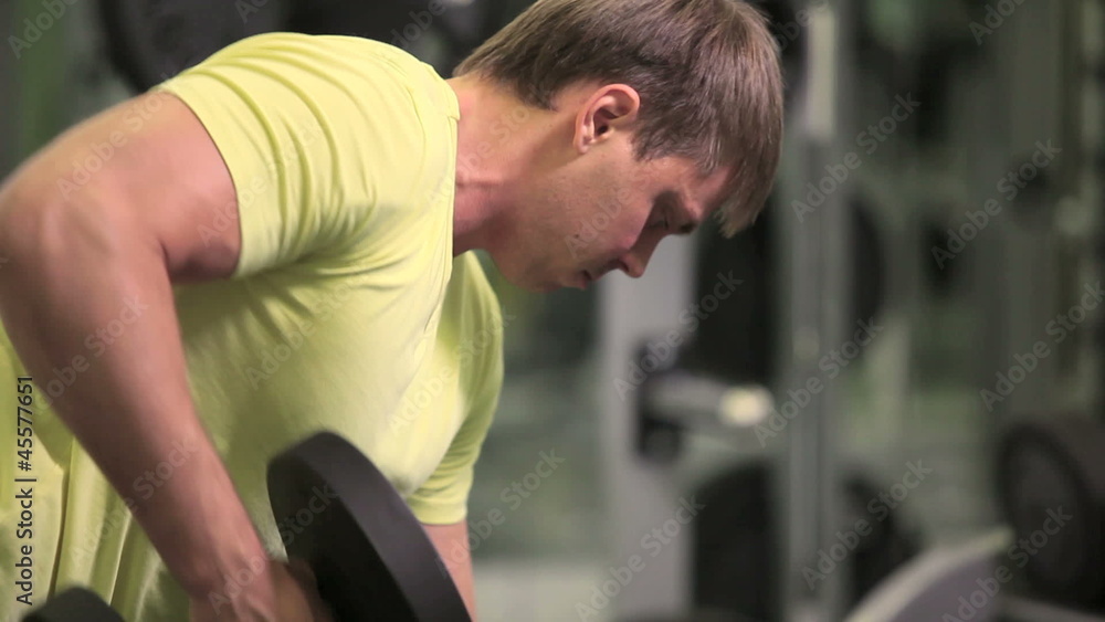 Muscular man lifting dumbbell in sport club Muscular man lifting dumbbell in sport club