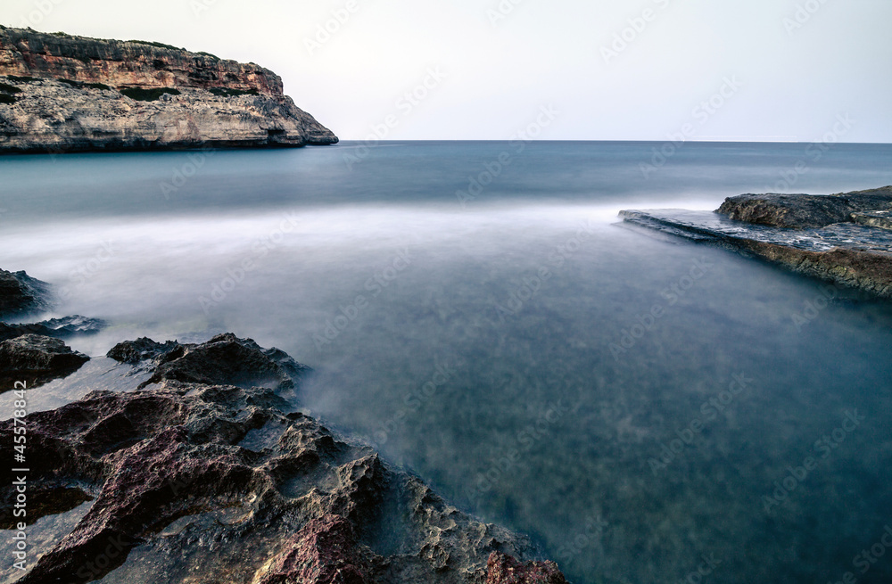 Sunset in rocky bay with blurred waters on Majorca