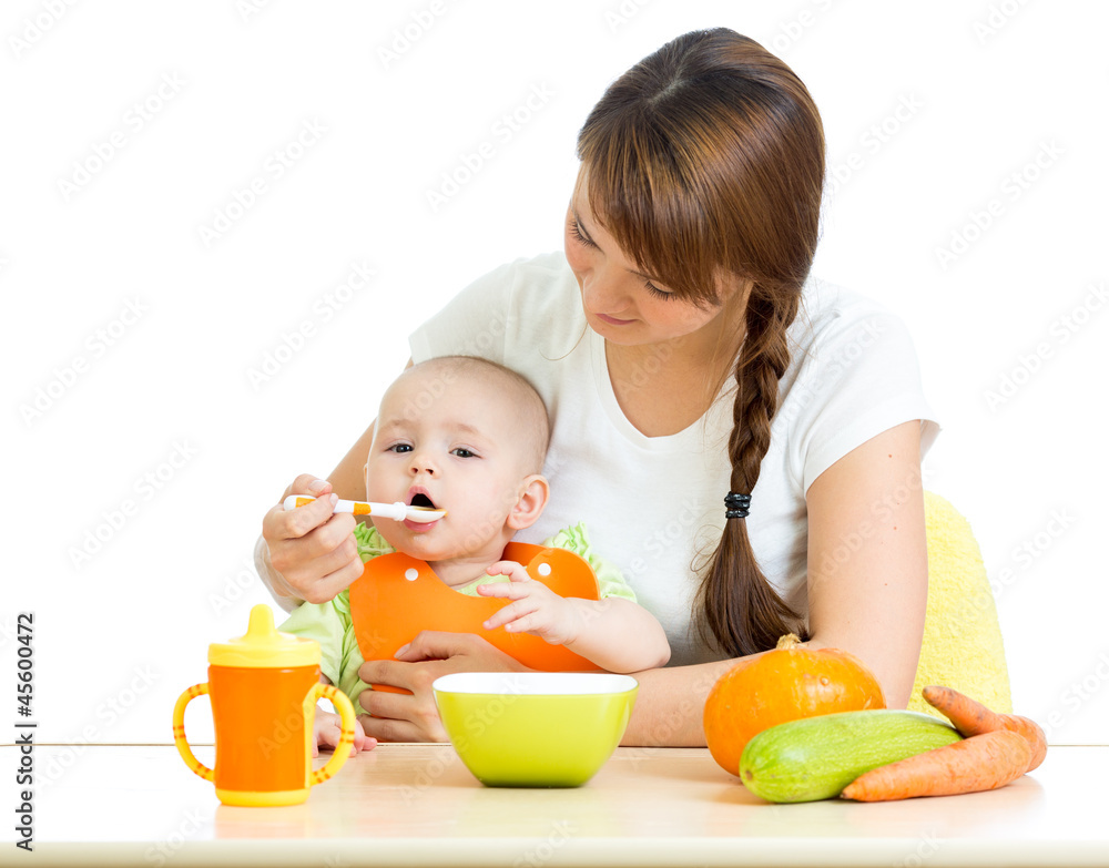 young mother spoon feeding her baby boy isolated on white young mother spoon feeding her baby boy isolated on white