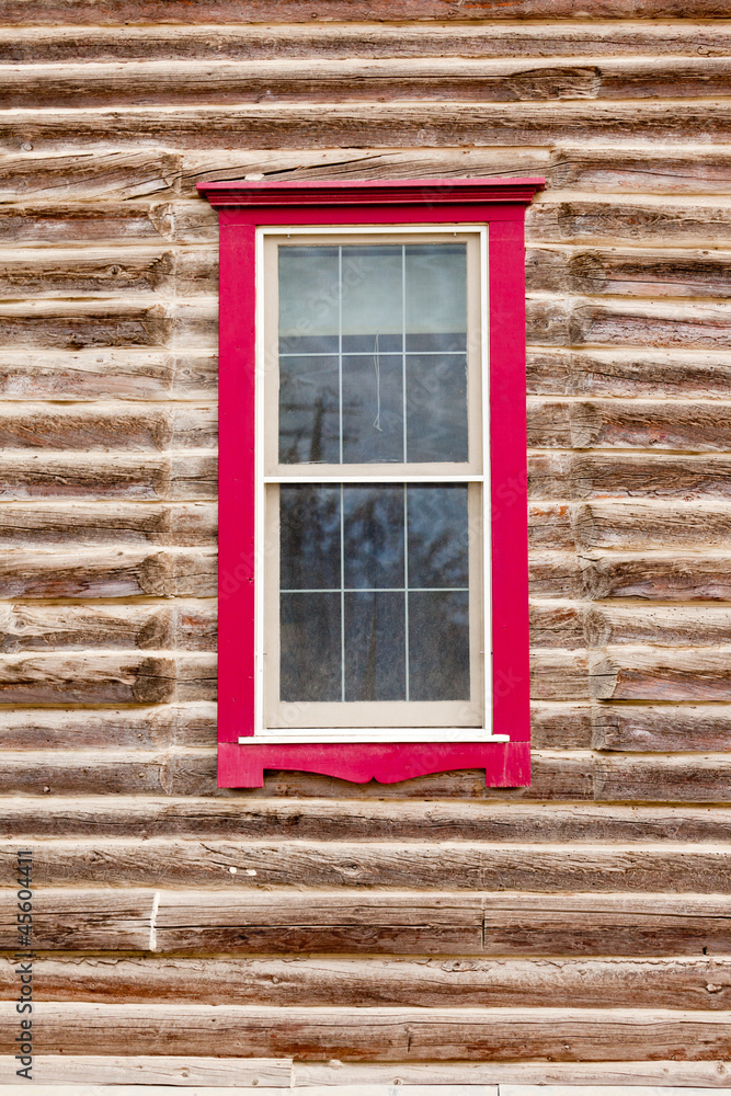 Fototapeta premium Red framed window in log house wall architecture