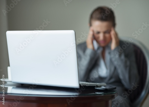 Closeup on desk with phone and laptop and stressed business woma photo