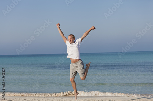 Fröhlicher Mann springt lachend am Strand Querformat