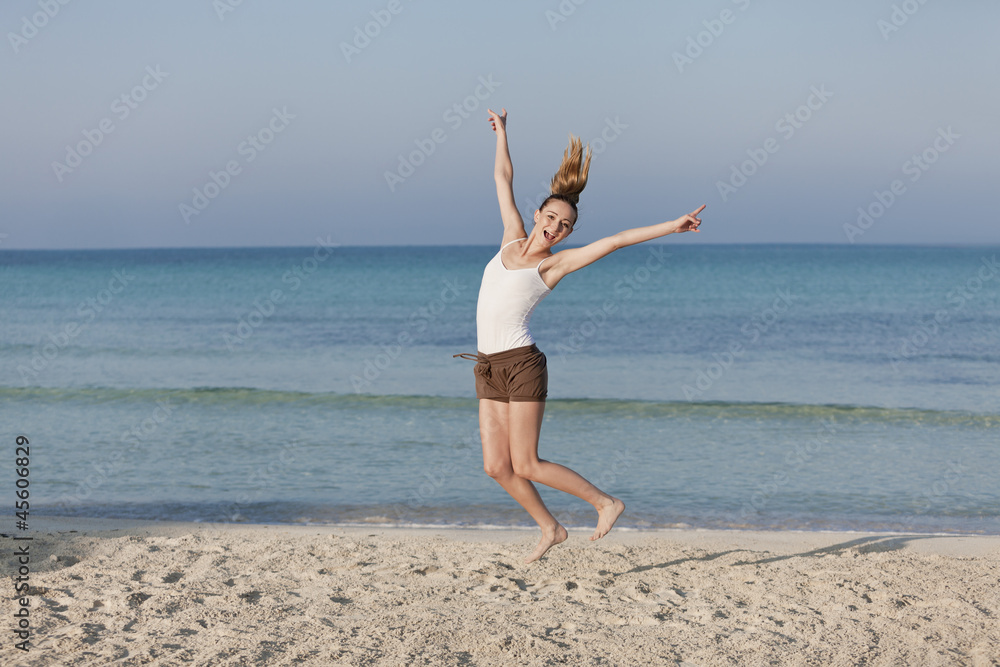 Fröhliche Frau springt lachend am Starnd Querformat Fröhliche Frau springt lachend am Starnd Querformat