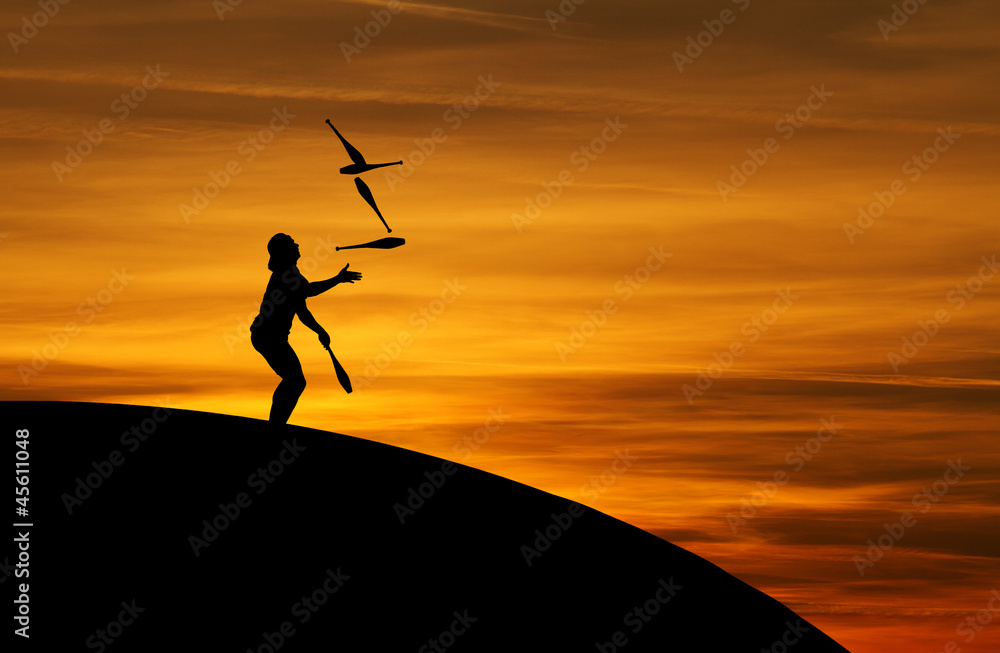 juggler in sunset with five juggling clubs