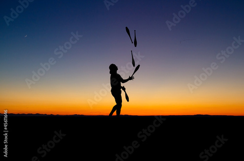 juggler in sunset with five juggling clubs © Alex Koch