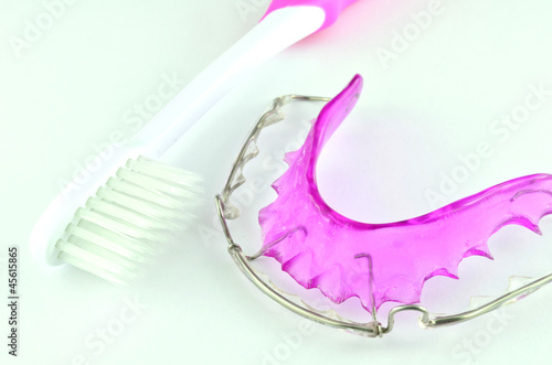 Close up of purple dental braces and toothbrush isolated on whit