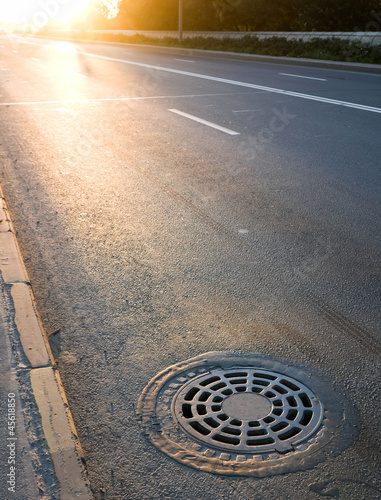 Sewer manhole cover on the roadside photo