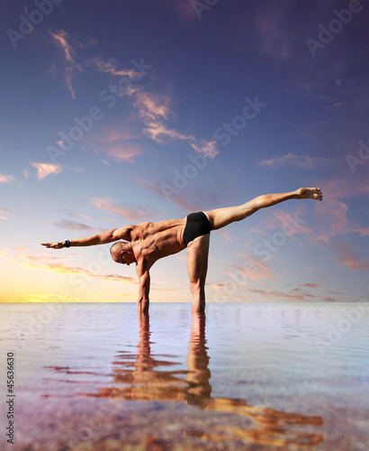 Man doing yoga exercise standing into the water