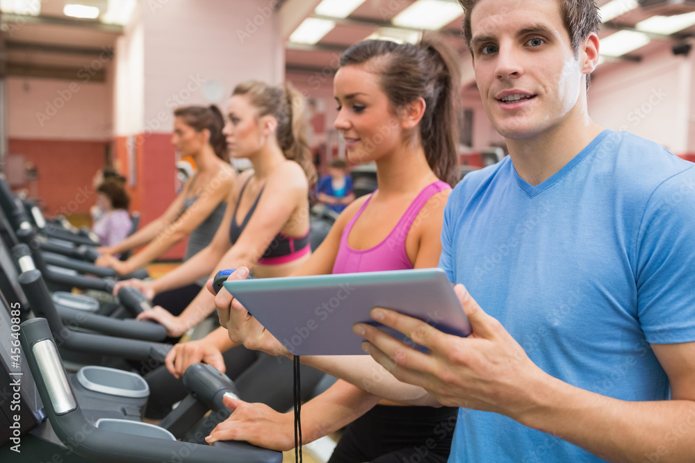 Male gym instructor with women on treadmills
