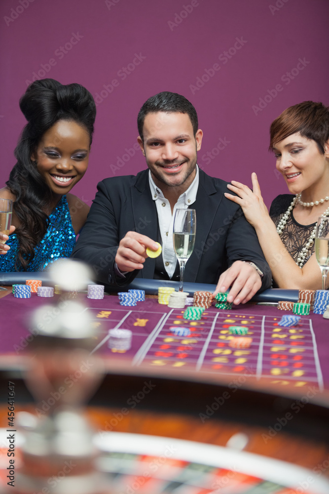 Man playing roulette with two women Man playing roulette with two women