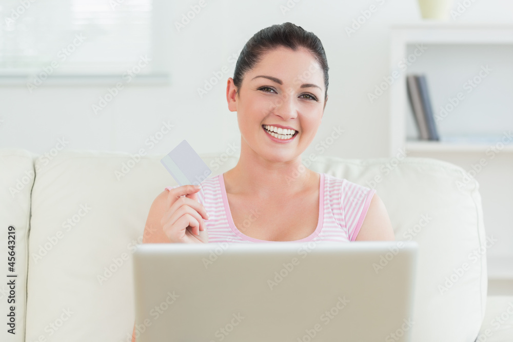 Smiling woman using a laptop and holding a credit card Smiling woman using a laptop and holding a credit card
