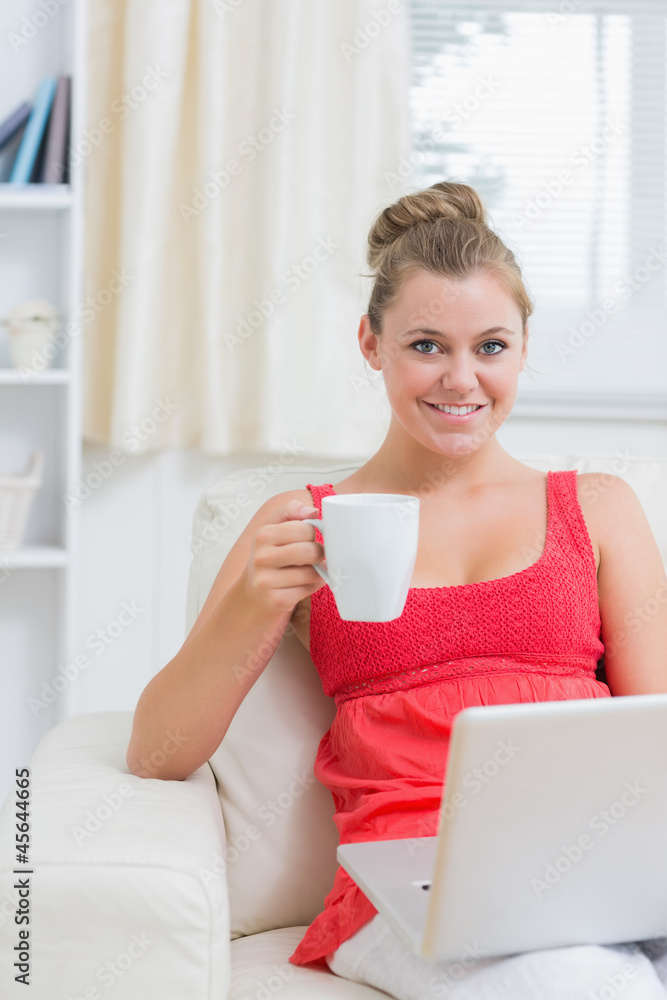 Woman drinking coffee while typing on laptop Woman drinking coffee while typing on laptop