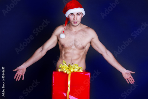 Portrait of a handsome muscular young man in Santa Claus hat