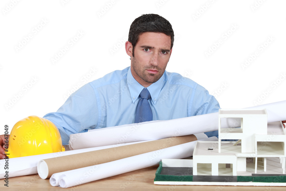 handsome architect posing near model and blueprints handsome architect posing near model and blueprints