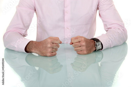 Man resting fists on glass table