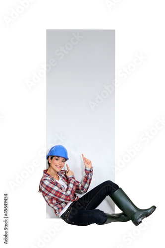 Female builder sat by blank poster © auremar