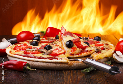 Hot pizza with oven fire on background