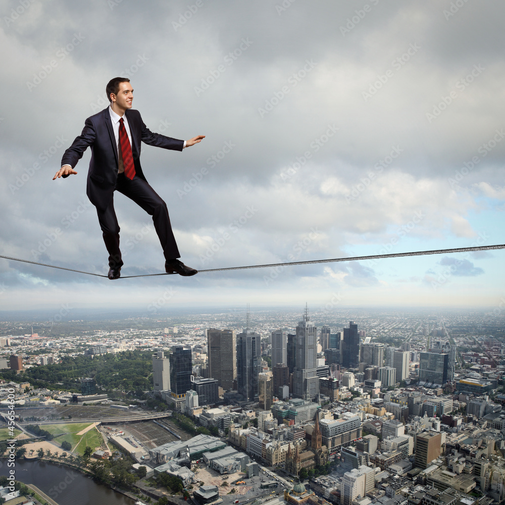 Balancing businessman and cityscape Balancing businessman and cityscape