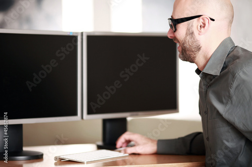 Mann im Büro vor PC Bildschirmen