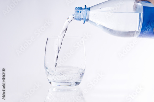 Wasserflasche beim Eingießen von Wasser in ein Glas