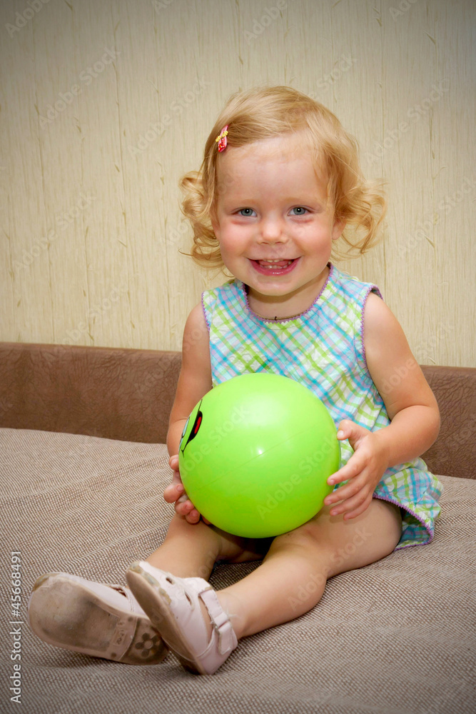 Fototapeta premium The little blond smiling baby girl with ball