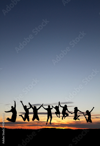 silhouette of friends jumping on beach in sunset