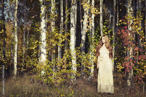 Fashion portrait of a beautiful young woman in autumn forest