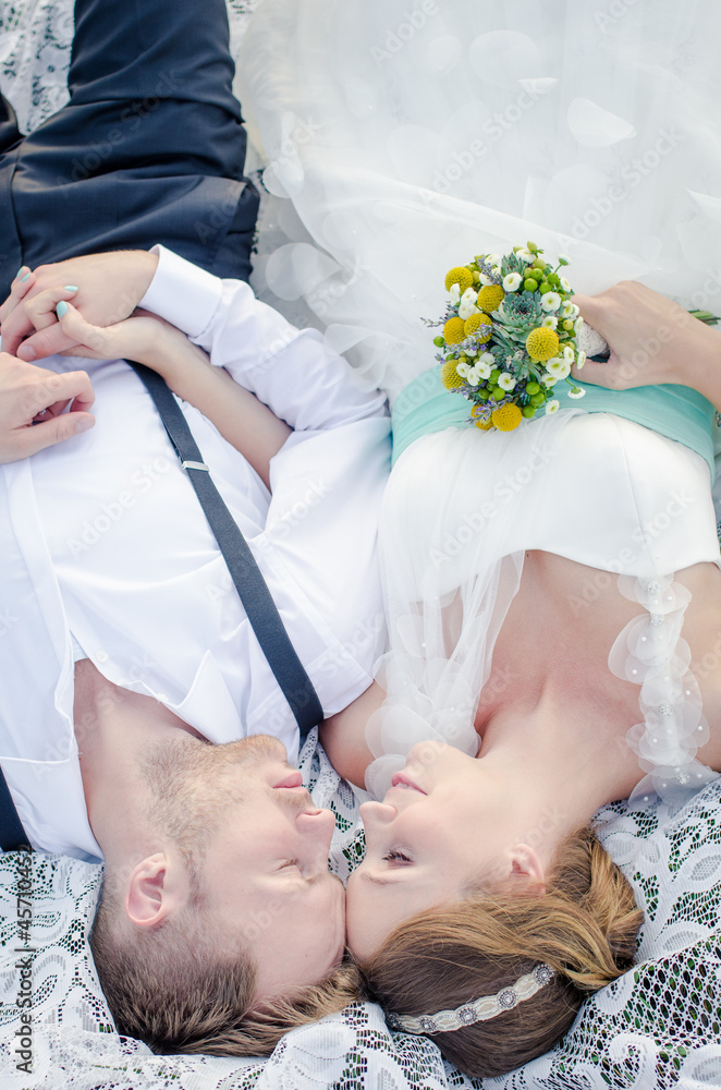 A bride and a groom lying on the grass