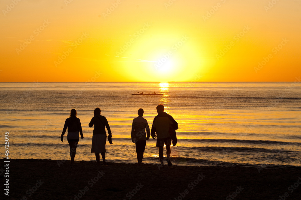 Family going for at swim at the beach at sunset